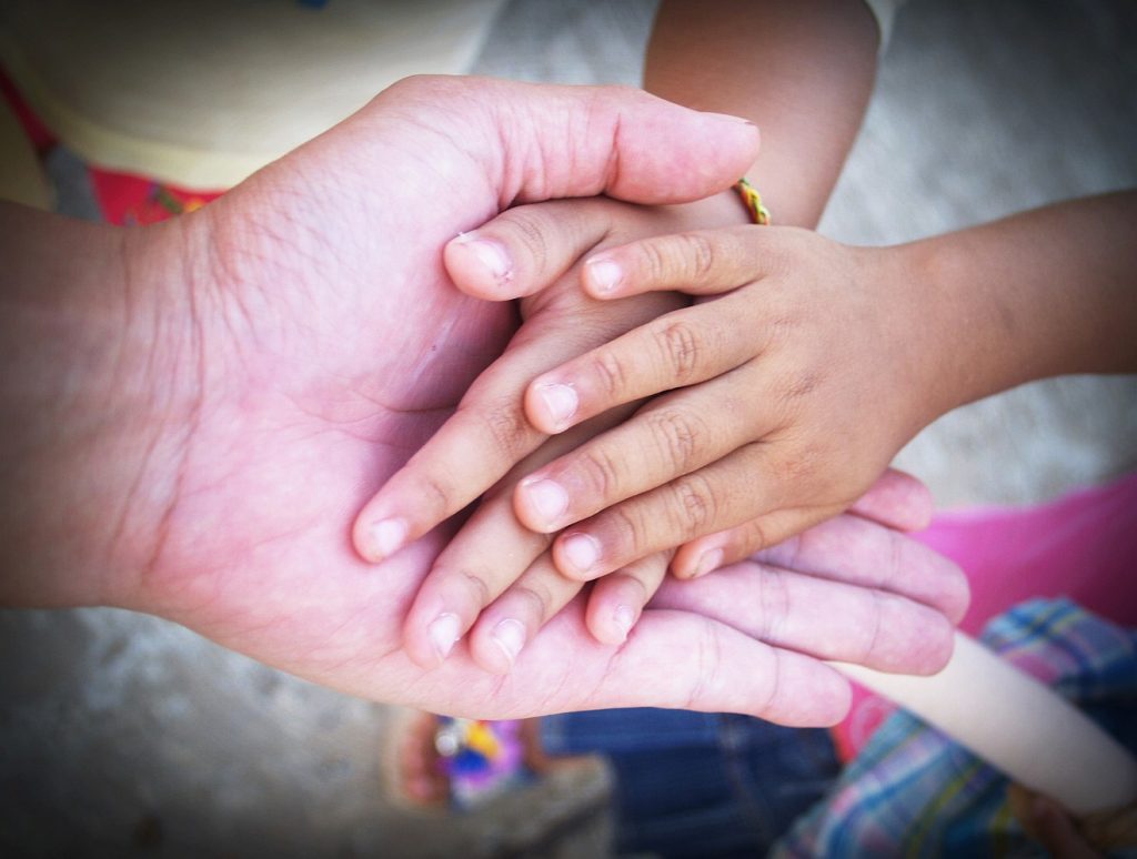 Kindeskinder bis ins dritte und vierte Glied: Eine alte Hand hält zwei Kinderhände.