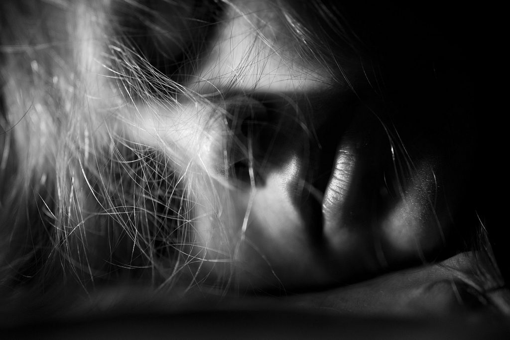 Friedlich einschlagen - in der Ewigkeit aufwachen? Das Gesicht einer Frau in schwarzweiß, auf der Seite liegend, mit geschlossenen Augen, schlafend