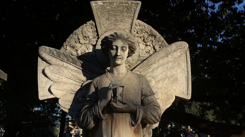 Der Stimme des Engels gehorchen: Die Statue eines Engels mit Flügeln und einer Sanduhr in der Hand auf einem Friedhof