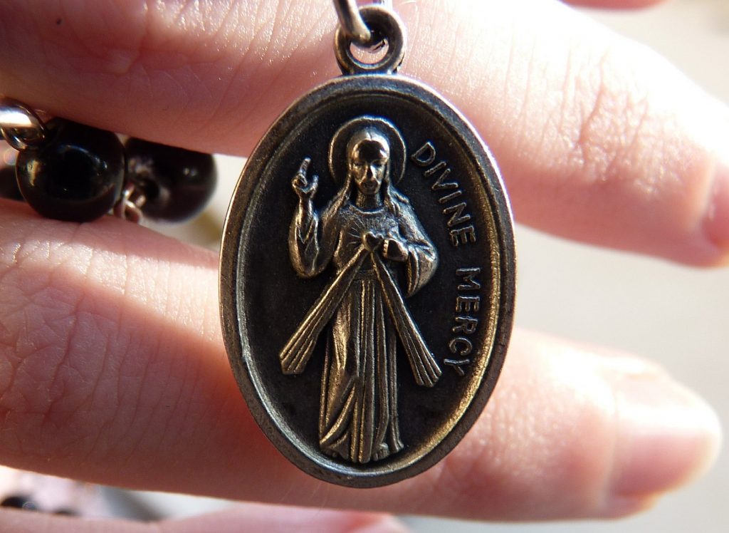 Verdiente Gnade: Ein Elliptisches Bronze-Medaillon an einem Rosenkranz mit der Inschrift "Divine Mercy" = "Göttliche Gnade" und dem segnenden Christus