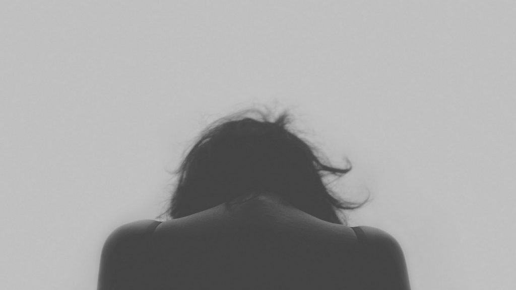 "Selig sind, die da Leid tragen": Eine Frau mit gesenktem Kopf, von hinten fotografiert, alles grau in grau