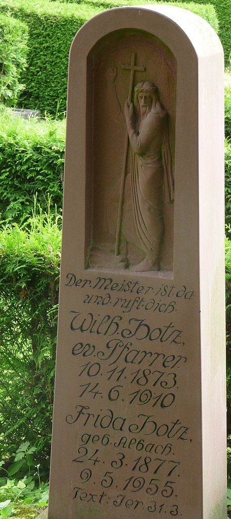 Das Sandstein-Grabmal eines Pfarrers mit Jesus: "Der Meister ist da und ruft dich"