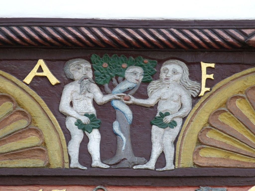 Eine Darstellung an einem Fachwerkhaus: Adam und Eva reichen einander den Apfel, schon bekleidet mit Feigenblättern, zwischen ihnen steht ein Apfelbaum mit der Schlange