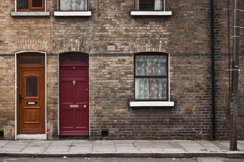 Die Fassade eines Hauses in Dublin mit alten verwitterten Mauern aus Ziegeln, zwei schmale Türen sind nebeneinander zu sehen und ein Fenster daneben.