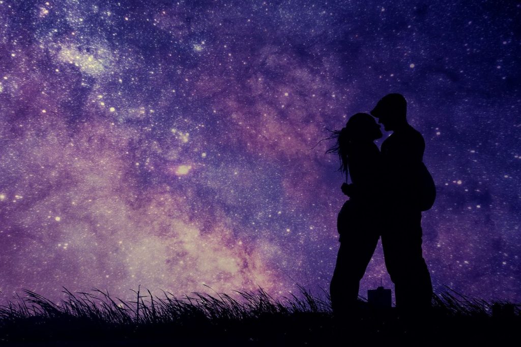 Silhouette eines Liebespaares, das sich küsst, vor einem sternenübersäten Nachthimmel.