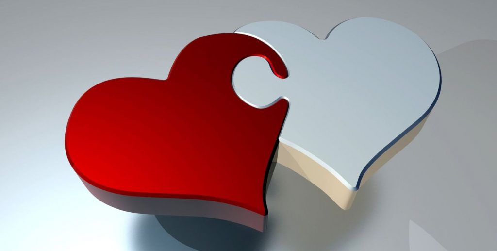 Ein rotes und ein weißes Herz sind wie Puzzleteile miteinander verbunden
