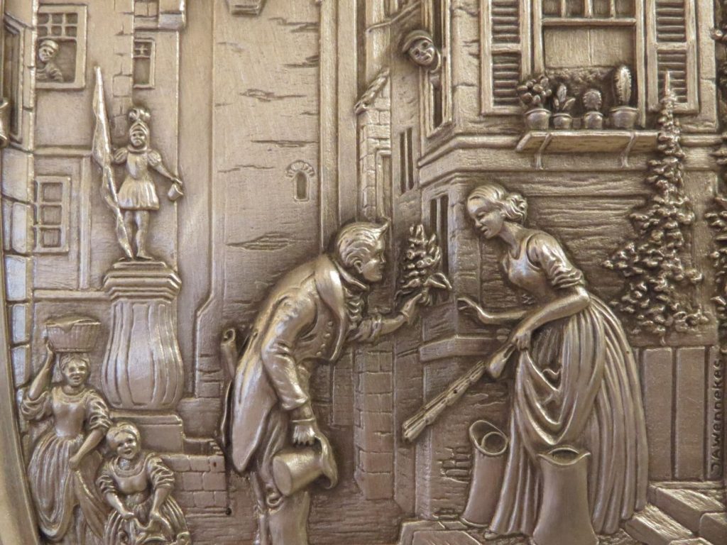 Ausschnitt aus einem Reliefteller, gestaltet nach einem Bild von Spitzweg, über einen jungen Mann, der seiner Geliebten einen Strauß Blumen überreicht.