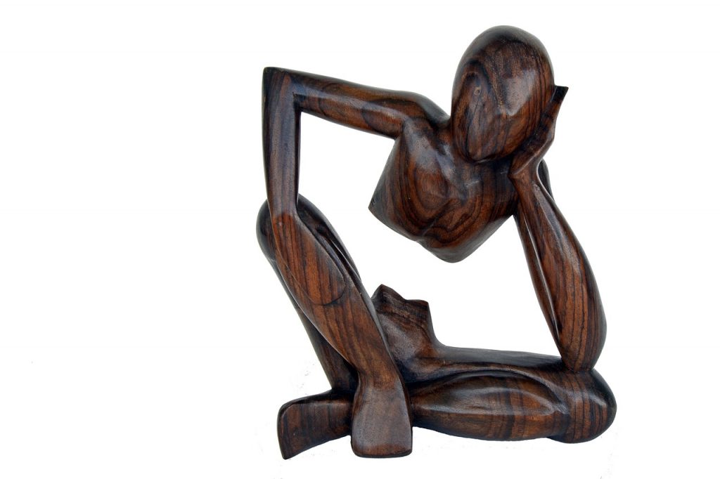 Die aus Holz geschnitzte Figur eines Mannes, der nachdenkt - den Kopf auf den linken Arm gestützt. Unter dem Brustkorb fehlt ihm der Bauch.