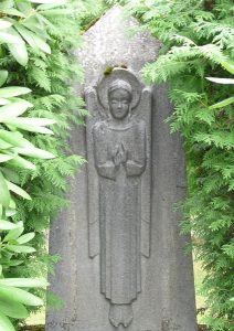 Ein streng blickender Engel als Relief auf einem hohen Grabstein