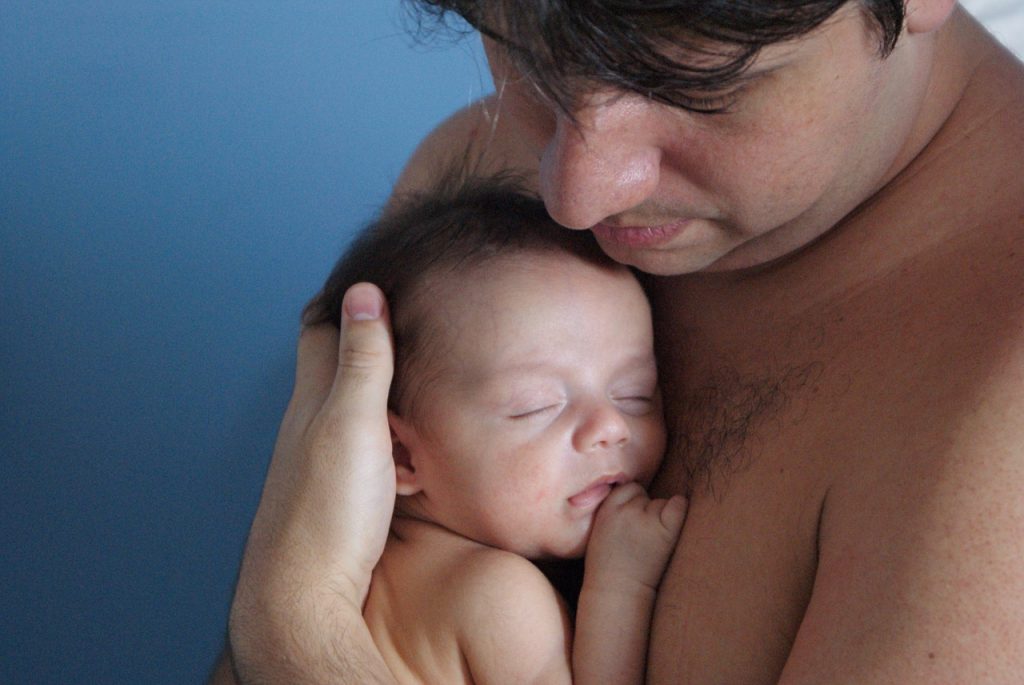 Ein Vater hält sein Baby im Arm vor seiner Brust