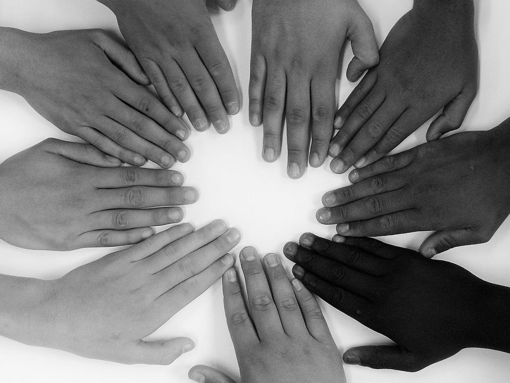 Hände verschiedener Hautfarben im Kreis - Symbol einer menschlichen Kirche