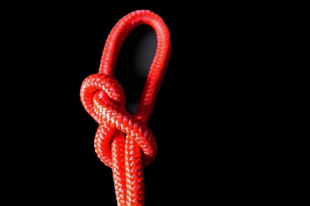 Der Knoten eines roten Seils vor schwarzem Hintergrund
