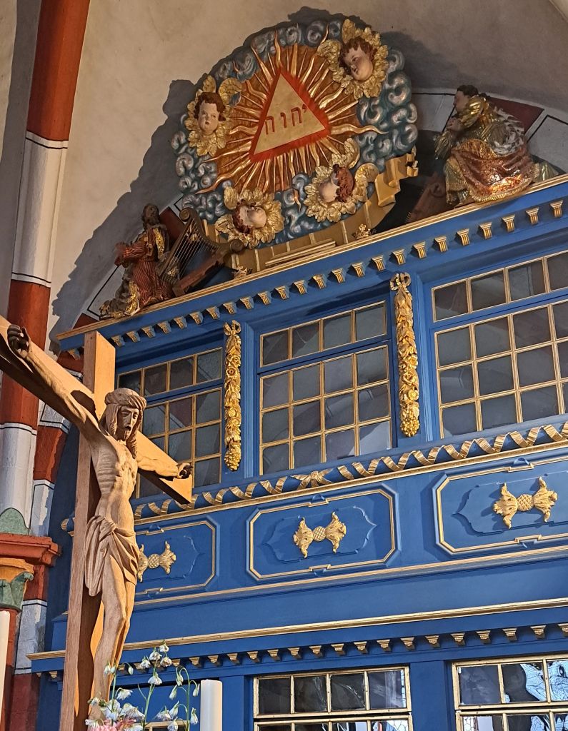 Eine kreisrunde Darstellung mit dem Schriftzug JHWH in einem Dreieck mit Strahlenkranz ist in der Kirche zu Laubach über dem Grafensitz angebracht, den die fürstliche Familie von ihrer Residenz aus direkt erreichen konnte. Unten links ist das Altarkreuz zu sehen.